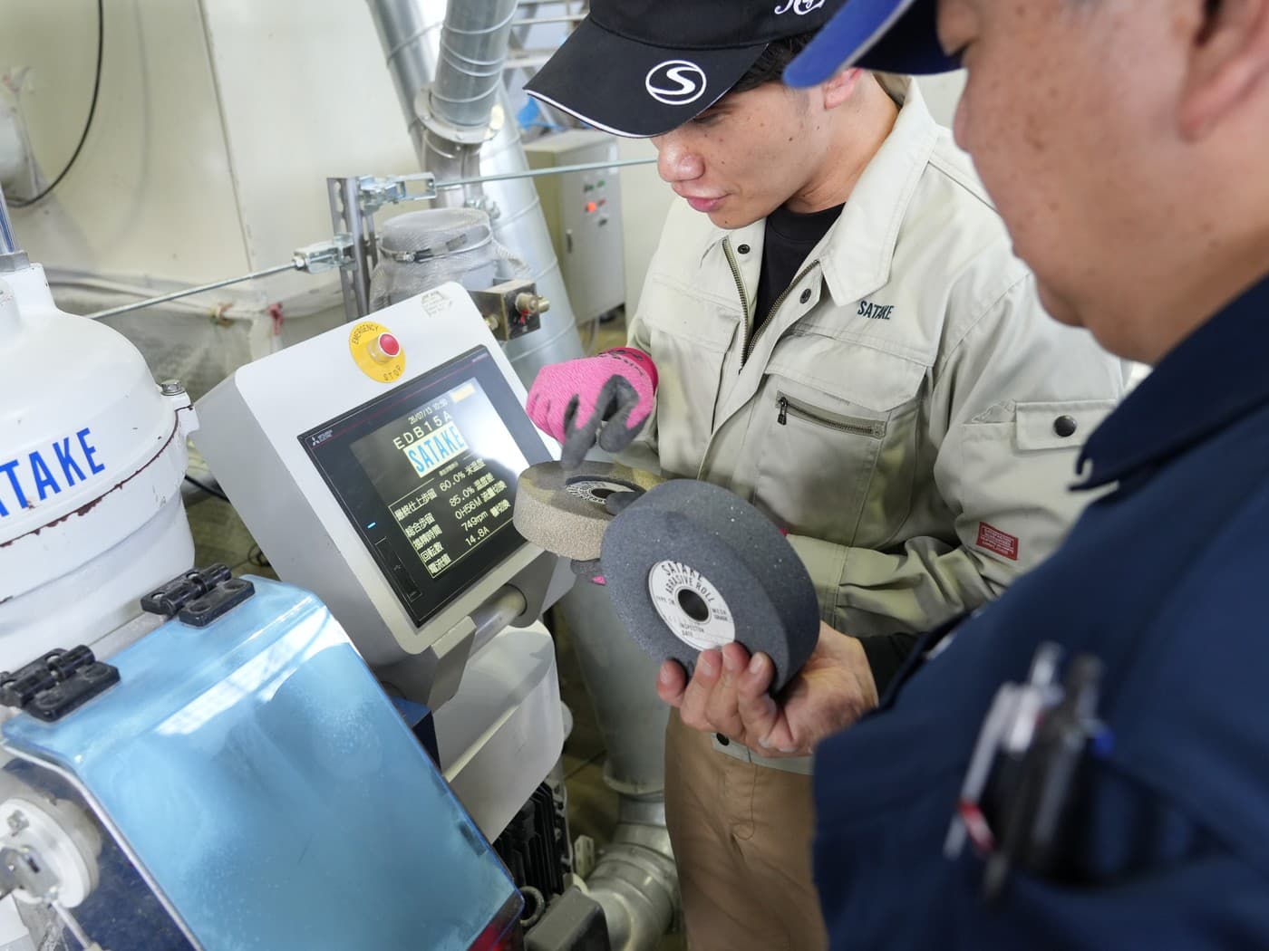 精米機の前で砥石ロールを手に検討する開発メンバー
